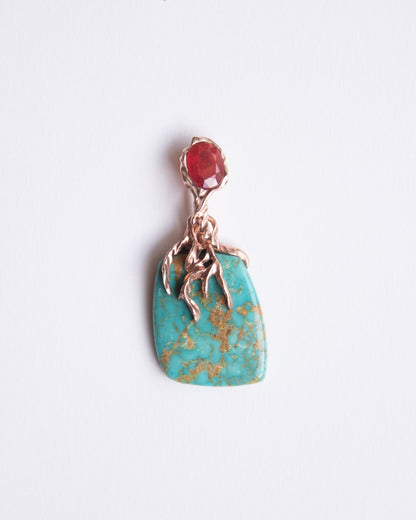 front view of a pendant featuring free-form natural turquoise and oval-shaped orange sapphire set in sterling silver plated with 18k rose gold