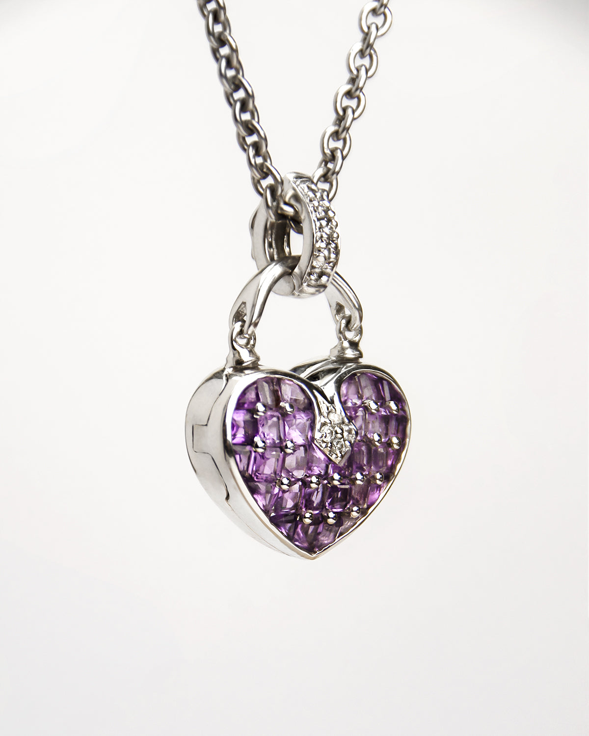 angled view of a heart-shaped locket set with amethysts and diamonds in a modern, high-polished 18K white gold setting