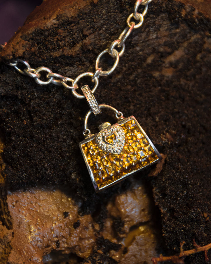 front view of a pendant with citrine and diamonds set in 18K white gold, styled creatively on a chocolate cake slice