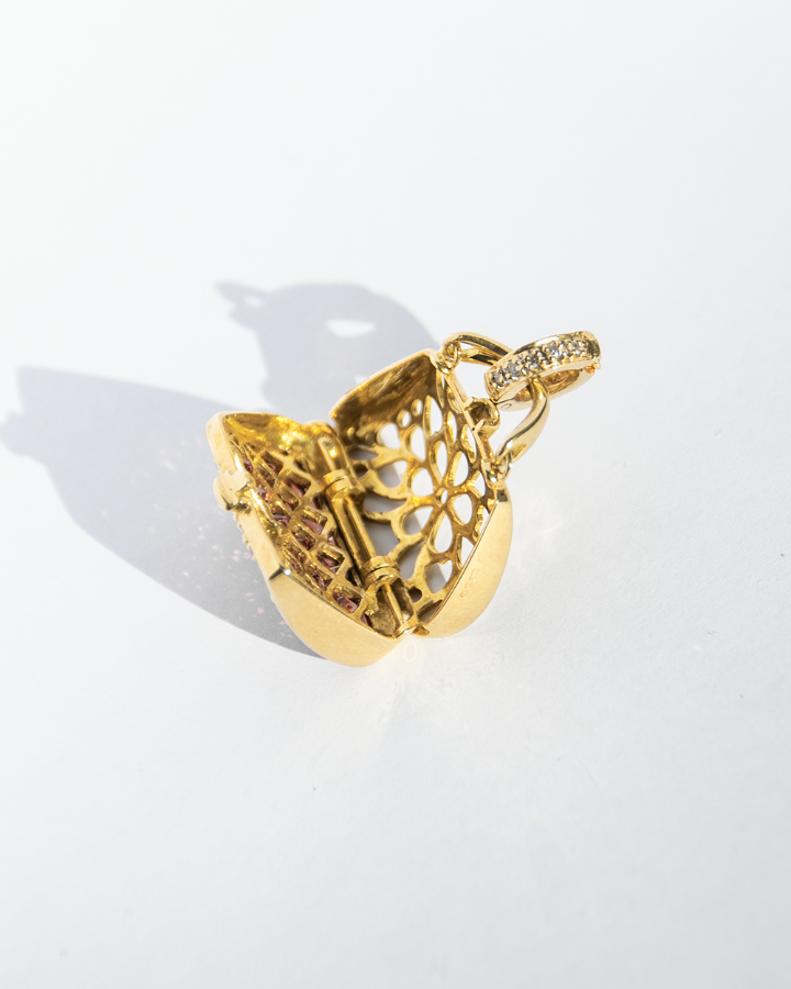 inside of an 18K gold locket, revealing a pierced frame and subtle shine