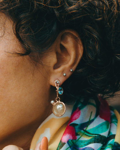 Model wearing unique Nisi Pebble earring set in gold plated silver wwith sapphires, garnets and freshwater pearls