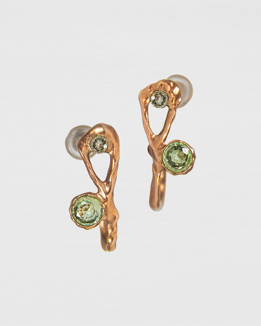 close-up of hoop earrings featuring green sapphires and diamonds set in a free-form abstract gold-plated silver setting