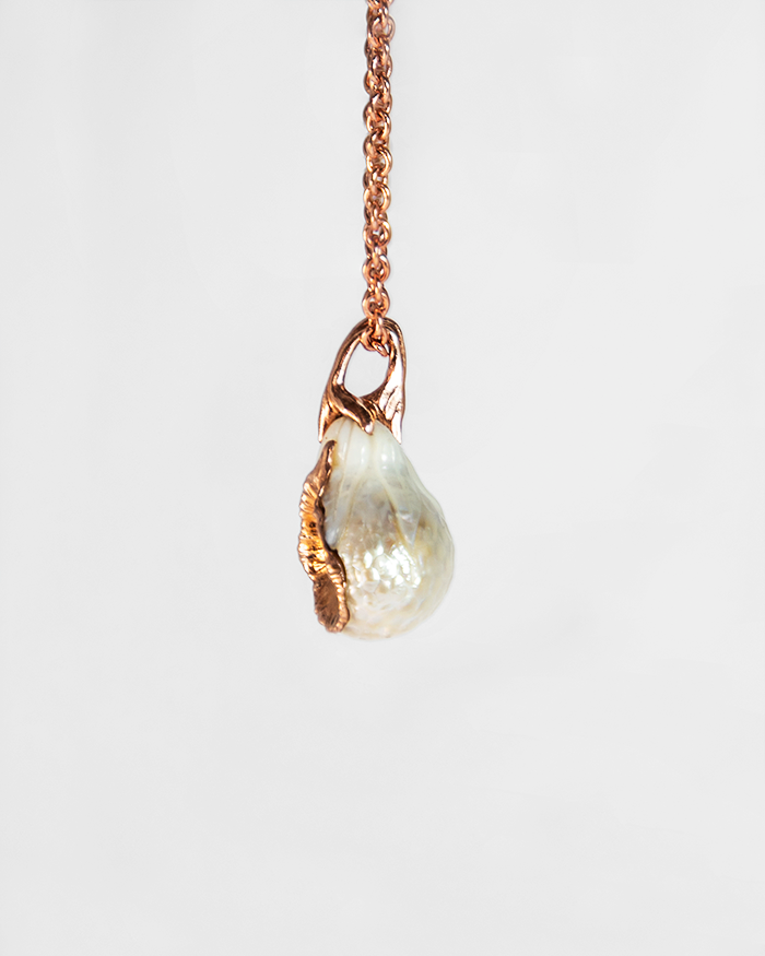 side profile of a pendant with a free-form rose gold-plated sterling silver setting, highlighting the sculpted design that elegantly cradles the pearl