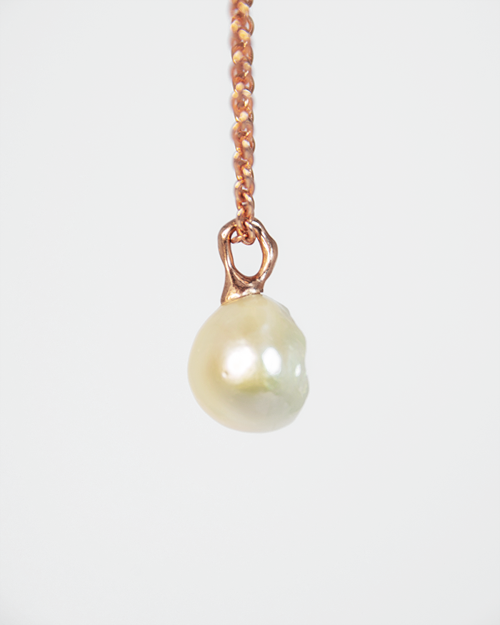 side profile of a pendant with an abstract gold-plated silver setting, highlighting the sculptural design that elegantly displays the pearl