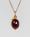front view of a reversible pendant in 18K rose gold-plated silver cradling a ruby in the centre with citrine and moonstone accents