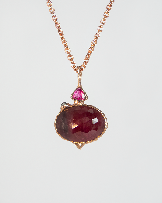 front view of a reversible silver pendant, featuring a ruby in the centre with side stones of moonstone and pink tourmaline