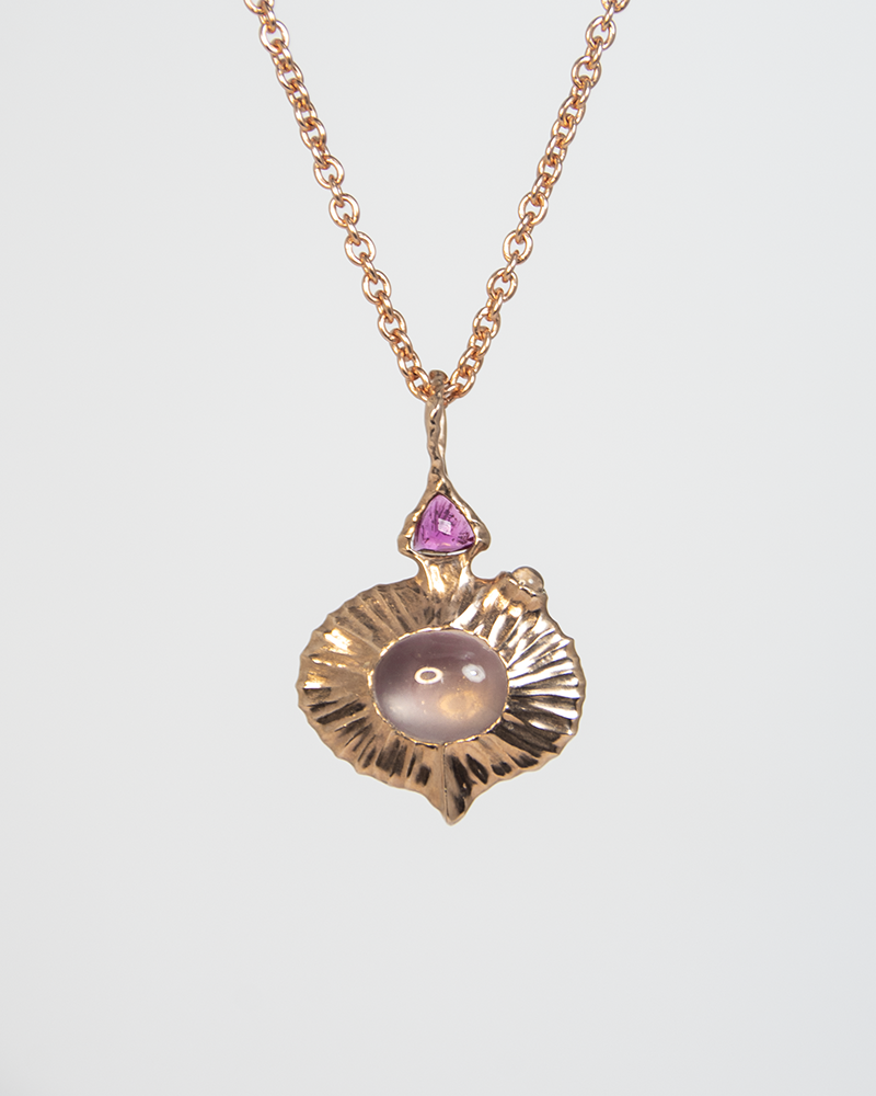 a reversible silver pendant, showing a rose quartz oval cabochon in the centre with pink tourmaline trillion-cut and moonstone cabochon on the side