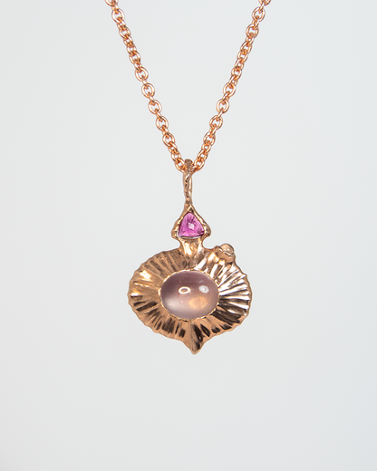 a reversible silver pendant, showing a rose quartz oval cabochon in the centre with pink tourmaline trillion-cut and moonstone cabochon on the side