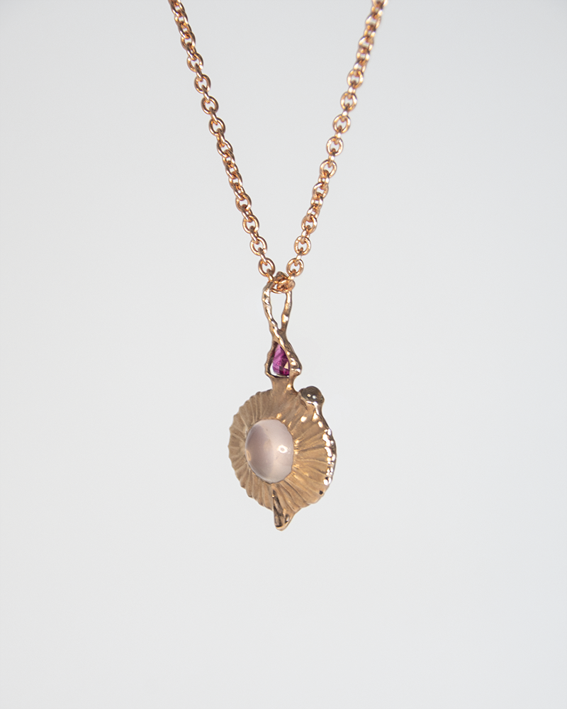 angled view of a pendant with a free-form rose gold-plated silver setting, showcasing the rose quartz oval cabochon in the middle