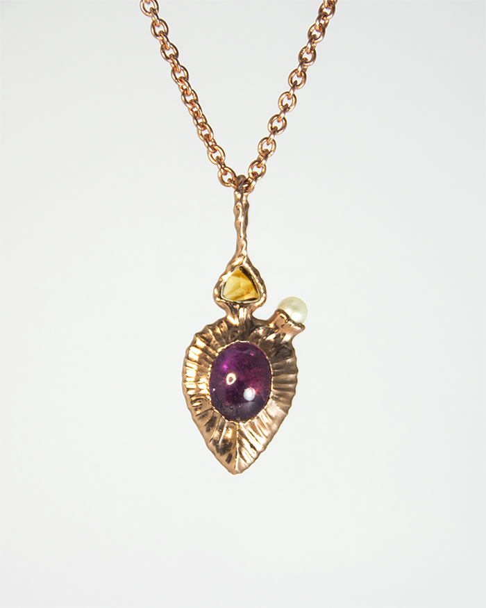 reverse side of a pendant with a satin finished setting, revealing a pink tourmaline oval cabochon complementing the obverse