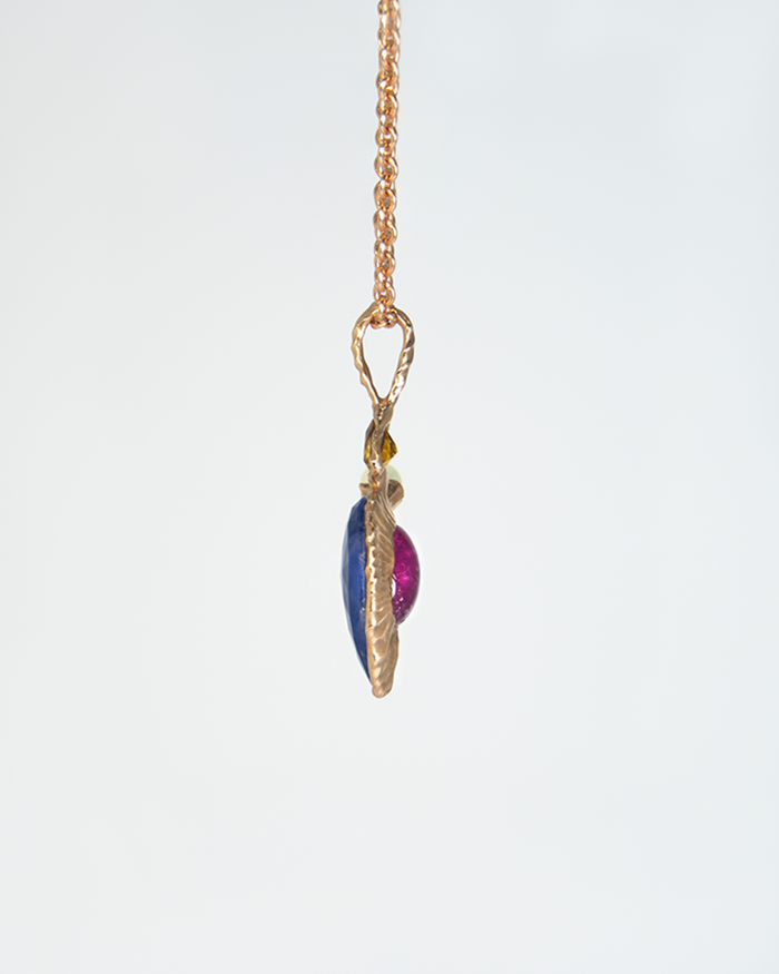 side profile of a pendant, highlighting the reversible design that elegantly holds the blue sapphire, rubellite, citrine, and white freshwater pearl