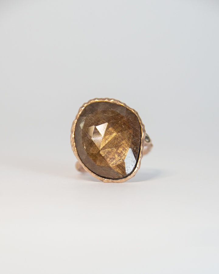 top face of a ring featuring a gold-sheen sapphire and diamond set in a free-form sterling silver setting with rose gold plating