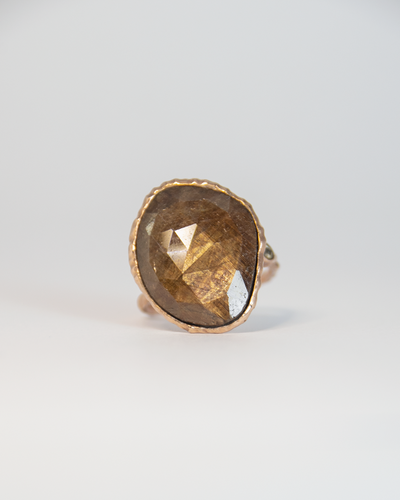 top face of a ring featuring a gold-sheen sapphire and diamond set in a free-form sterling silver setting with rose gold plating