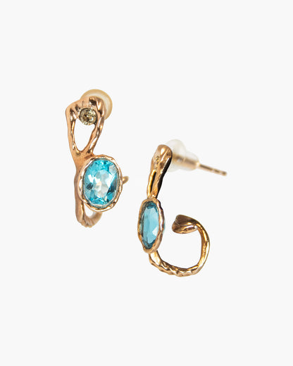 A pair of gold-plated silver hoop earrings with a free-form sculpted design showcasing blue topaz and diamonds