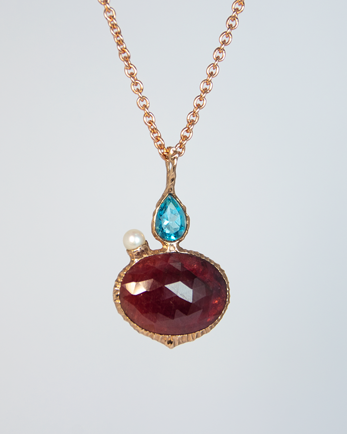 reverse side of a rose gold-plated silver pendant, displaying a rose-cut ruby in the centre with a free-form setting