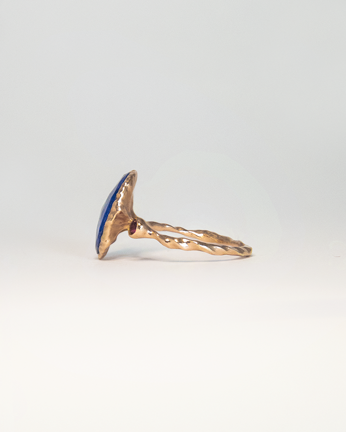 angled view of silver ring ring, revealing the round faceted ruby on one side of the free-form band