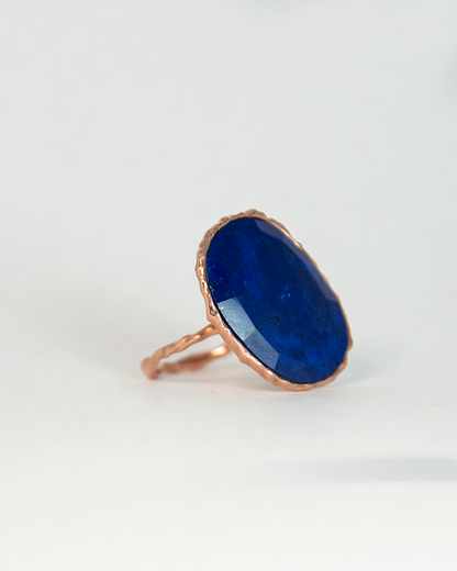 angled view of gold-plated silver ring, emphasising the deep blue lapis lazuli centre stone in a free-form setting