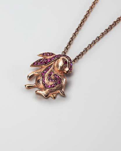 angled view of Rabbit Pendant, featuring rubies set in sterling silver with rose gold plating. 