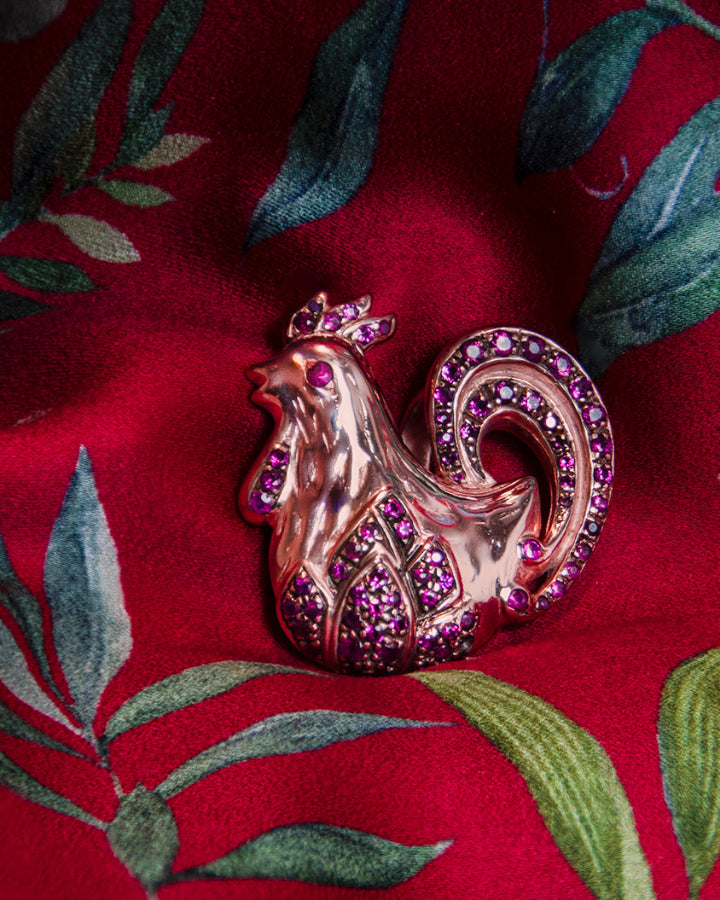 front view of a rooster-shaped pendant in sterling silver with rose gold plating, featuring rubies